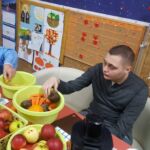 Dwóch chłopców siedzi prze stole. Obierają owoce i warzywa.